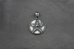 Detail of vintage silver pentagram star pendant on dark textured fabric background