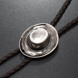 Close-up of vintage silver alloy cowboy hat pendant on braided bolo tie leather cord