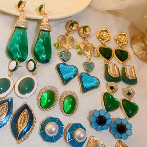 Detailed flat lay of assorted vintage heart and teardrop earrings in emerald green and gold