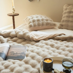 Detailed texture of beige faux rabbit fur blanket and pillow with embossed square pattern