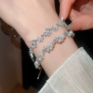 Close-up of butterfly zircon bracelet and round pearl jewelry on woman's wrist
