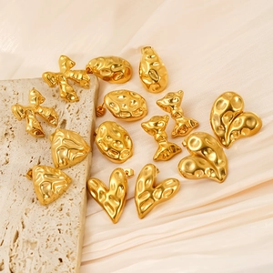 Hammered 18k gold plated bow and heart stud earrings on a textured stone surface