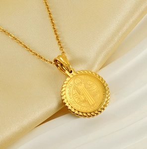 Macro view of gold 18K plated Saint Benedict medal pendant on silk background