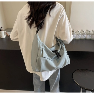 Detailed drape effect of light blue canvas tote bag worn by model in cafe setting