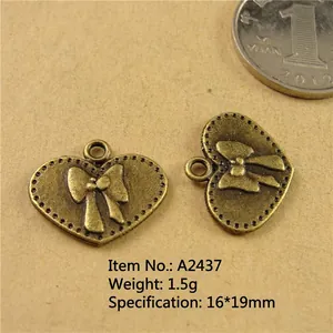 Macro shot of 16x19mm heart bow pendants in antique bronze with a size reference coin