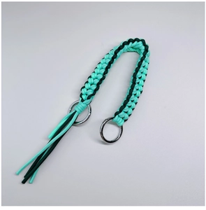 Macro view of mint green woven paracord strap with tassels and silver metal rings