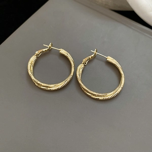 Macro shot of gold textured interlocking hoop earrings with detailed metallic finish