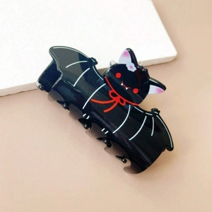 Close-up of black cartoon bat hair claw clip with red collar and pink ears detail