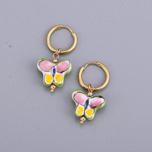 Detail of butterfly drop earrings with colorful enamel glaze on golden steel rings