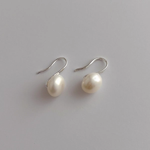 Detailed macro view of natural freshwater pearl earrings with elegant silver hooks