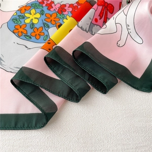 Detail van platliggende roze zijden sjaal met cartoon konijn en bloemenpatronen