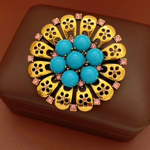 Detail of vintage flower brooch with blue beads and pink crystals on leather box