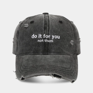 Detailed view of washed black cotton baseball cap with white embroidery and distressed holes