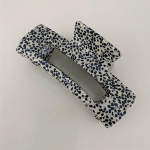 Detail view of large rectangular hair claw clip with black and white dotted texture