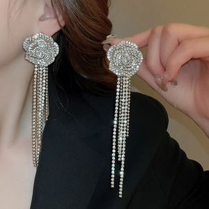 Close-up of silver-plated flower earrings with shimmering tassels worn by a fashion model