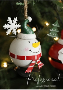 Macro shot of painted metal snowman ornament with festive scarf on Christmas tree branches