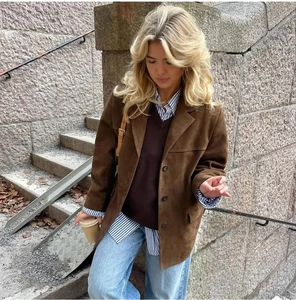 Detailed view of a vintage brown suede jacket texture and layered styling on street model