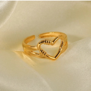 Detail shot of golden heart hug ring on silk background showing hollowed craftsmanship