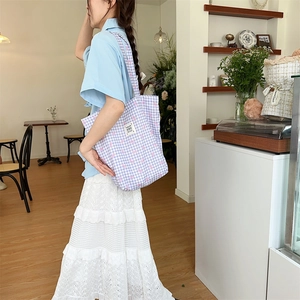 Detail of purple plaid canvas tote bag with pink ribbon print and shoulder strap