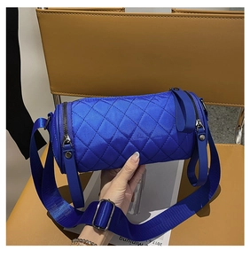 Close-up of quilted royal blue cylinder crossbody bag with wide shoulder strap