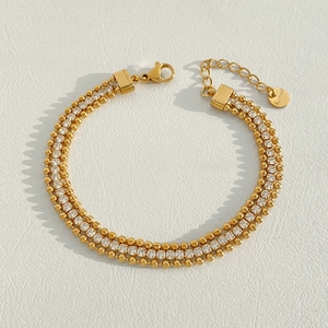 Close-up of triple-layered gold bead bracelet with zircon stones and S.steel tag