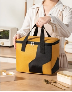 Spacious insulated yellow and black lunch bag with durable handles on a kitchen counter