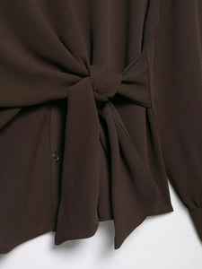 Detail of dark coffee crepe set showing side waist tie-knot and small button closure