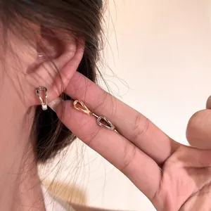 Detailed view of minimalist double-layered geometric gold and silver earrings on ear