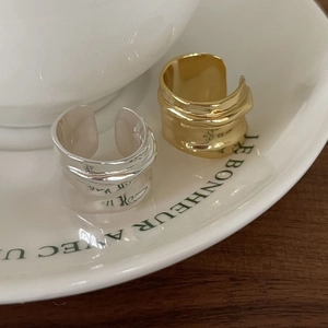 Adjustable 925 sterling silver wide band rings in gold and silver finish on a ceramic cup
