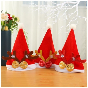 Three red velvet Christmas hats with glitter reindeer antlers and bows on wooden table