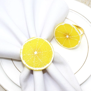 Detail of vibrant yellow lemon slice napkin ring with realistic fruit texture on white linen