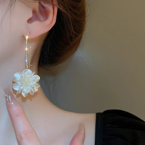 Détail macro de boucles d'oreilles dorées avec cristaux et fleurs blanches nacrées élégantes