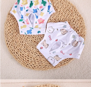 Detailed view of floral and bear print dog sanitary pants with elastic waist on a straw mat