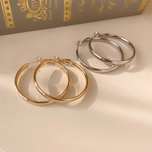 Dettaglio di orecchini a cerchio placcati oro e argento su un libro d'epoca