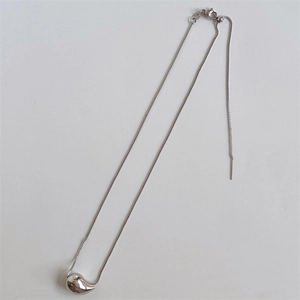 Macro shot of silver teardrop pendant necklace with polished finish and box chain