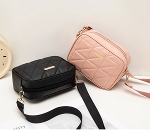 Detail of quilted small crossbody bag with adjustable wide strap and gold hardware