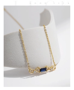 Close-up of S925 silver necklace with a deep blue gemstone and gold scroll detail