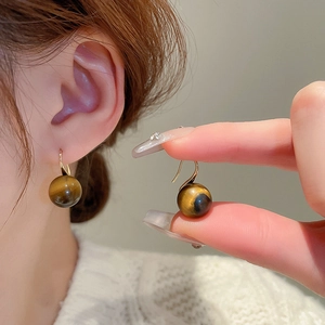 Detail of gold-plated earrings featuring natural brown tiger eye stones with cat eye effect
