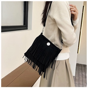 Close-up of black tassel crossbody bag with adjustable strap worn by a female model
