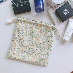 Floral cotton drawstring pouch shown with cosmetics on a white wooden background