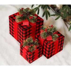 Detail of red and black buffalo plaid Christmas gift boxes with pine cones and festive lights