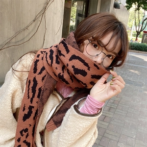 Outdoor shot of a woman wearing a thick leopard print knitted scarf in brown and black