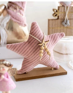 Pink fabric star ornament with silver stripes on a wooden base for Christmas table decor