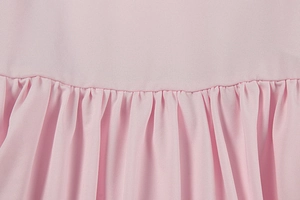 Close-up of pleated pink fabric texture and fine stitching detail on summer dress