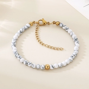 Détail de perles de marbre blanc et fermoir mousqueton doré sur bracelet perles