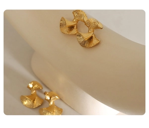 Close-up of golden vintage fan-shaped earrings with embossed metallic texture and folds
