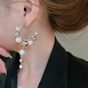Detail of geometric C-shaped earrings with pearls and silver chain fringe on model