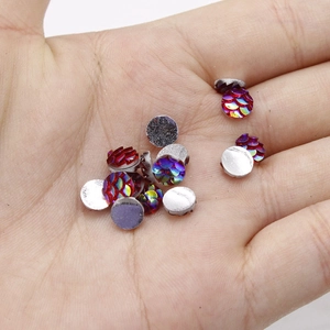 Macro shot of 6mm resin fish scale cabochons with colorful AB finish in a palm