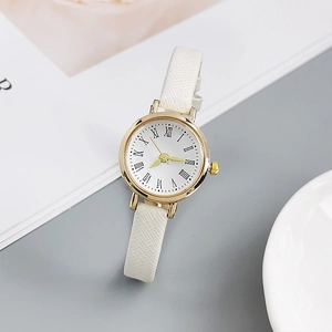 Detail of minimalist gold quartz watch with white leather strap and Roman numerals