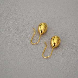 Macro detail of polished gold drop earrings with minimalist teardrop design